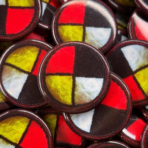 Può includere: Primo piano di un mucchio di bottoni rotondi e colorati con un design a quattro quarti in rosso, giallo, bianco e nero. I bottoni sono tutti della stessa dimensione e hanno una finitura lucida e lucida.