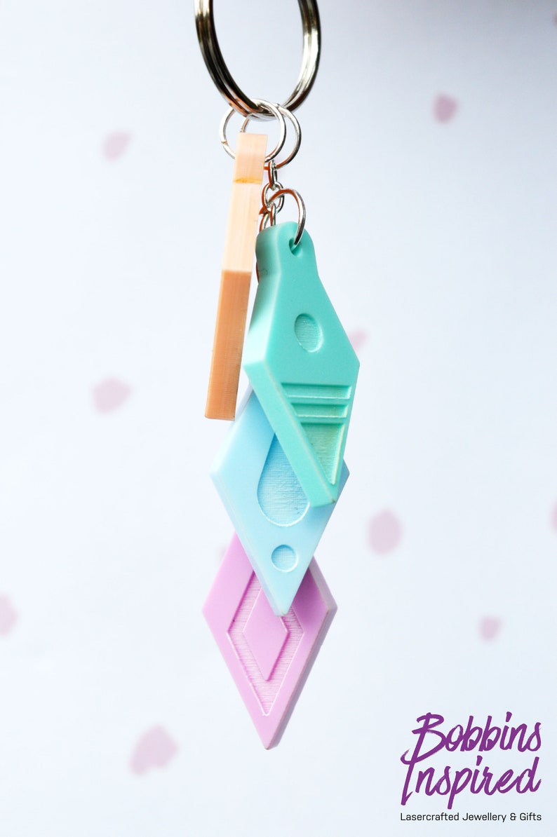 Peut inclure: Un porte-cl&eacute;s avec trois breloques&nbsp;: un diamant rose clair, un diamant bleu clair et un diamant turquoise clair avec une bande blanche. Les breloques sont attach&eacute;es &agrave; un anneau de cl&eacute; argent&eacute;.