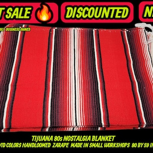 May include: A red, white, and black striped Tijuana 80s Nostalgia blanket. The hand-loomed blanket is approximately 80 x 59 inches. The image includes the text "HOT SALE", "DISCOUNTED", and "NEW".
