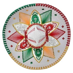 May include: A white sombrero featuring a central crown and a wide brim decorated with intricate embroidery in red, green, and orange thread. The design includes star-shaped patterns, gold sequin accents, and a braided border in red and green.