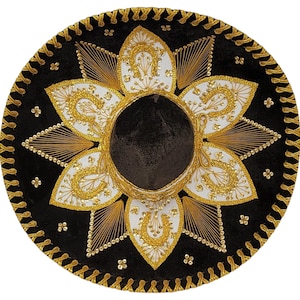 Op de afbeelding: Een zwarte sombrero met ingewikkeld goudkleurig en wit borduurwerk in een bloemmotief. De brede rand is afgewerkt met een gouden gevlochten bies en de kroon is omringd door witte bloemblaadjes, elk versierd met een goudkleurig hoefijzervormig ontwerp.