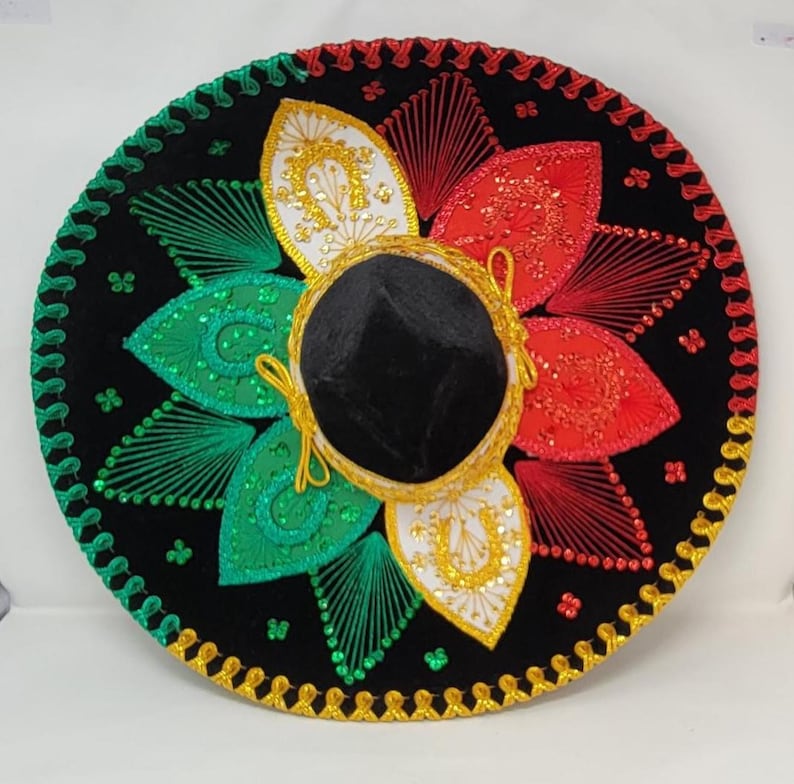 May include: A black sombrero with colorful embroidery. The hat features red, green, and white floral designs, gold trim, and a black velvet crown. The brim is decorated with gold and green stitching.