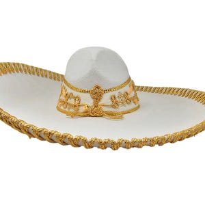 May include: A white sombrero featuring a wide brim and a high crown. The hat is decorated with intricate gold metallic embroidery and trim along the edge of the brim and around the base of the crown, including a gold cord detail at the front.