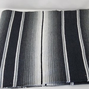 Peut inclure: Une couverture ray&eacute;e noire et blanche avec une bordure en franges. La couverture est faite d'un tissu doux et tiss&eacute;.