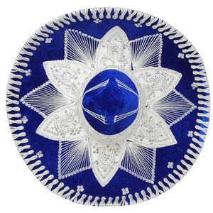 Op de afbeelding: Een levendige koningsblauwe sombrero met ingewikkeld zilverkleurig borduurwerk in een stervormig patroon rond de kroon. De brede rand is versierd met gedetailleerd zilverdraad en een geschulpte rand, wat zorgt voor een opvallend contrast.