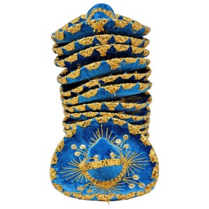 May include: A vertical stack of bright blue velvet sombreros, each featuring intricate gold metallic embroidery along the brim and crown. The hats are uniform in design, showcasing a vibrant blue fabric contrasted by detailed gold thread patterns.