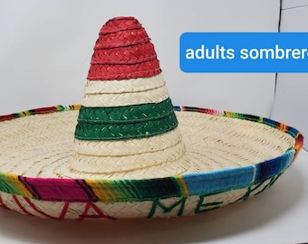 May include: A traditional sombrero with a wide brim and a tall, conical crown. The hat features a woven straw design with colorful trim in red, green, blue, and yellow. The text "adults sombrero" is in a blue box.