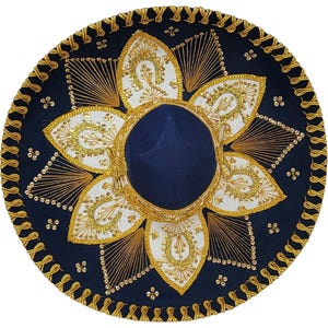 Op de afbeelding: Een donkerblauwe sombrero met een brede rand en een gouden gevlochten bies. De kroon en de rand zijn versierd met witte, bloembladachtige stoffen panelen, ingewikkeld goudkleurig borduurwerk en kleine gouden lovertjes in een bloemmotief.