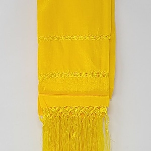 Peut inclure: Un châle tissé jaune vif avec une frange. Le châle présente un motif décoratif de lignes tissées.