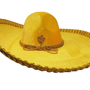 May include: A bright yellow sombrero featuring a wide brim and a high, rounded crown. The hat is decorated with metallic gold braided trim along the edge of the brim and around the base of the crown, which includes a decorative gold knot detail.