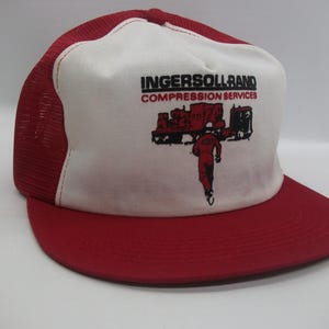 May include: Red and white trucker hat with the text "Ingersoll Rand Compression Services" and a graphic of a person working on a machine.