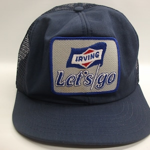 May include: A blue and white trucker hat with a patch that says "Irving Let's go" with a red and white flag logo.