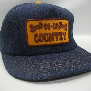 May include: A blue denim trucker hat with a brown and yellow patch that reads "CO-OP'S COUNTRY".