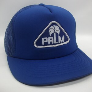 May include: A blue and white trucker hat with a palm tree logo and the word "PALM" in white lettering.