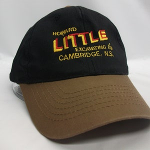 May include: Black and brown baseball cap with the embroidered text "Howard Little Excavating Ltd. Cambridge, N.S."