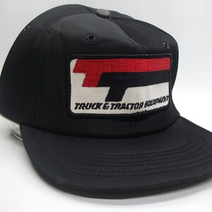 May include: Black trucker hat with a red, white and black embroidered patch that says "Truck & Tractor Equipment".