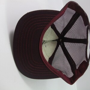 May include: A maroon baseball cap with a mesh back. The cap has a curved brim and a snap closure.