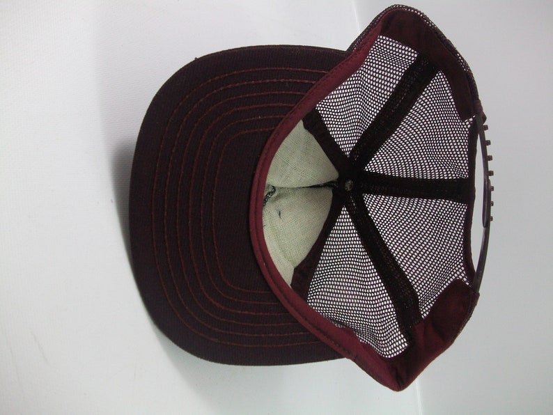 May include: A maroon baseball cap with a mesh back. The cap has a curved brim and a snap closure.