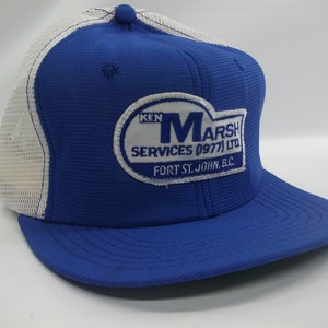 May include: Blue and white trucker hat with a white patch that says "Ken Marsh Services (977) LTD Fort St. John, B.C."
