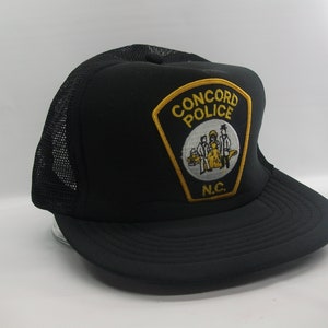 May include: Black mesh trucker hat with a yellow and black embroidered patch that says "CONCORD POLICE" and "N.C."