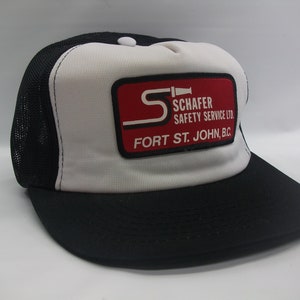 May include: A white and black trucker hat with a red and black patch that says "Schafer Safety Service Ltd. Fort St. John, B.C."