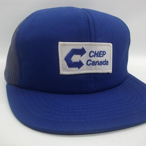 Peut inclure: Casquette de camionneur bleue et blanche avec un patch blanc qui dit "CHEP Canada" avec un logo d'un C stylisé avec des flèches.
