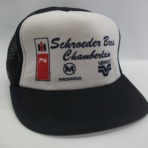 May include: A white and black trucker hat with the text "Schroeder Bros. Chamberlain" and logos for International Harvester, Morris, and Versatile.