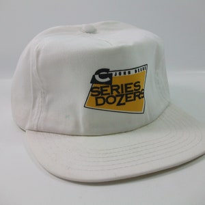 May include: White baseball cap with a yellow and black John Deere logo that says "Series Dozers".