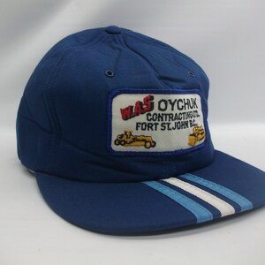 May include: Blue baseball cap with a white and blue striped brim. The cap has a patch on the front that says "WAS OYCHUK CONTRACTING LTD. FORT ST. JOHN B.C."