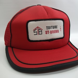 Peut inclure: Casquette de camionneur rouge et noire avec un patch blanc qui dit "TOITURE ST-BRUNO INC."