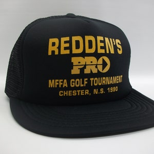 May include: Black mesh trucker hat with a gold embroidered logo that says "Redden's Pro" and "MFFA Golf Tournament Chester, N.S. 1990".