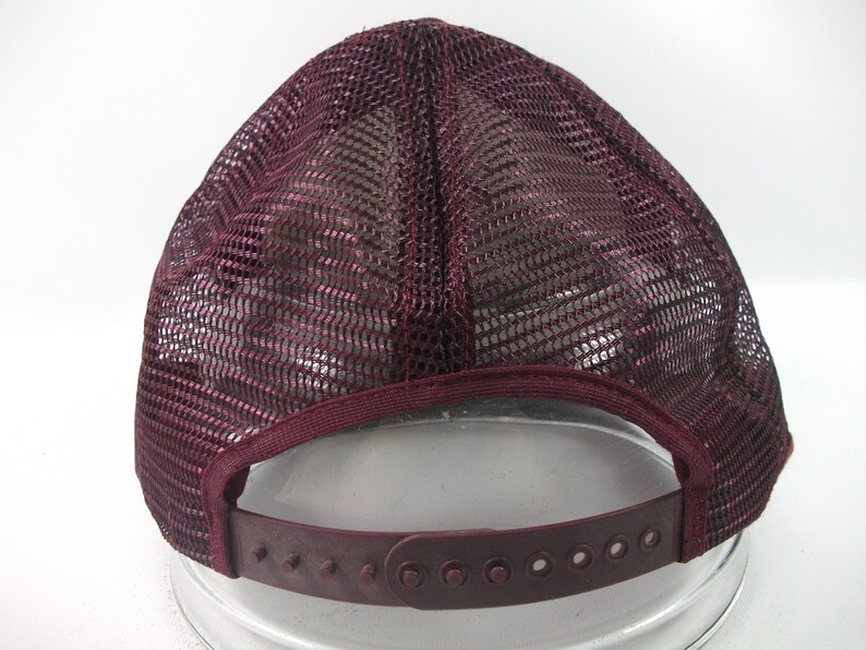 May include: A burgundy mesh trucker hat with a plastic adjustable strap in the back.