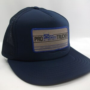 May include: A navy blue trucker hat with a brown patch that says "PRO TRUCKER" and "ENERGY EFFICIENCY FOR THE PROFESSIONAL TRUCKER".