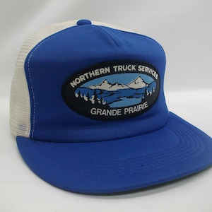 May include: Blue and white trucker hat with a black oval patch that says "Northern Truck Services Grande Prairie" with a mountain scene inside the oval.