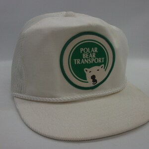 May include: White trucker hat with a green and white patch that says "Polar Bear Transport" and features a white polar bear with a green background.