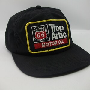 May include: Black baseball cap with a yellow, red, and white embroidered patch that says "Phillips 66 Trop Artic Motor Oil".