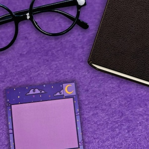 May include: A purple background with a black-framed round glasses, a brown leather-bound notebook, and a square purple sticky note pad. The sticky note pad has a purple border with a night sky design, including clouds, stars, and a crescent moon.