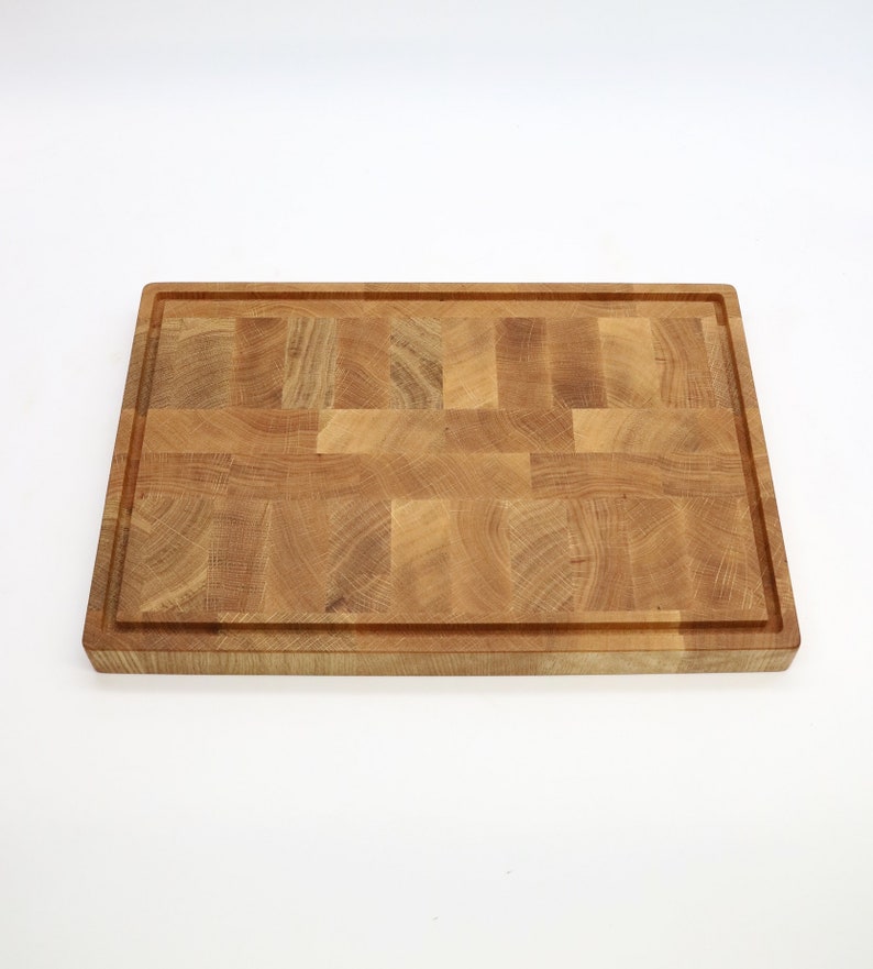 Op de afbeelding: Een groot, rechthoekig houten snijplank met een natuurlijke houtkleur. De plank is gemaakt van meerdere stukken hout die aan elkaar zijn gelijmd om een moza&iuml;ekpatroon te cre&euml;ren.