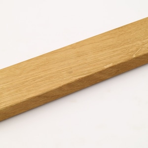 May include: A wooden wall mount with two holes for hanging. The mount is made of light brown wood and has a smooth finish.
