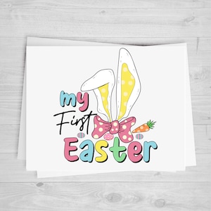 May include: A white card with the text "my first Easter" in colorful letters. The text is surrounded by a pink bow with white polka dots, bunny ears with yellow polka dots, and colorful Easter eggs.