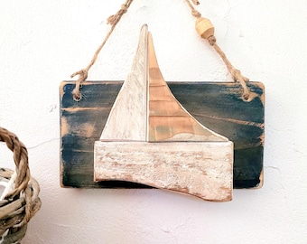 Dekoratives Wandbild mit einer Küstenlandschaft und einem Boot im Relief, gefertigt aus recyceltem Holz. Sorgt für maritimes Ambiente.