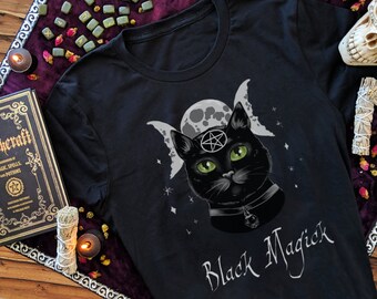 Pode incluir: Camiseta preta com um gato preto usando um pentagrama e um colar, cercado por uma lua tripla e estrelas. O texto "Black Magick" é impresso abaixo do gato.
