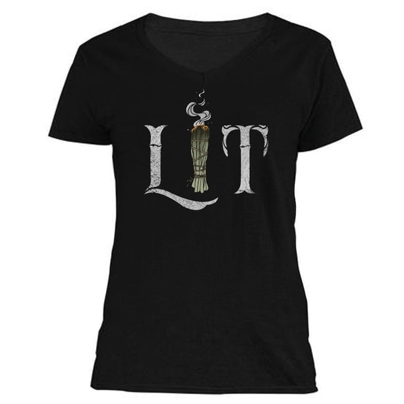 May include: Black v-neck t-shirt with the word "LIT" in distressed white lettering. The "I" is replaced with a bundle of burning sage, with smoke rising above it. The shirt is a casual, everyday wear item.