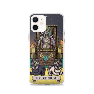 K&ouml;nnte beinhalten: Eine Handyh&uuml;lle mit einer farbenfrohen Illustration der Chariot-Karte aus einem Tarot-Deck. Die Karte zeigt eine mumienartige Figur in einem Wagen, der von zwei sphinxartigen Kreaturen gezogen wird. Die Karte ist vor einem sternenklaren Nachthimmel mit Pyramiden im Hintergrund platziert. Der Text "THE CHARIOT" ist am unteren Rand der Karte gedruckt.