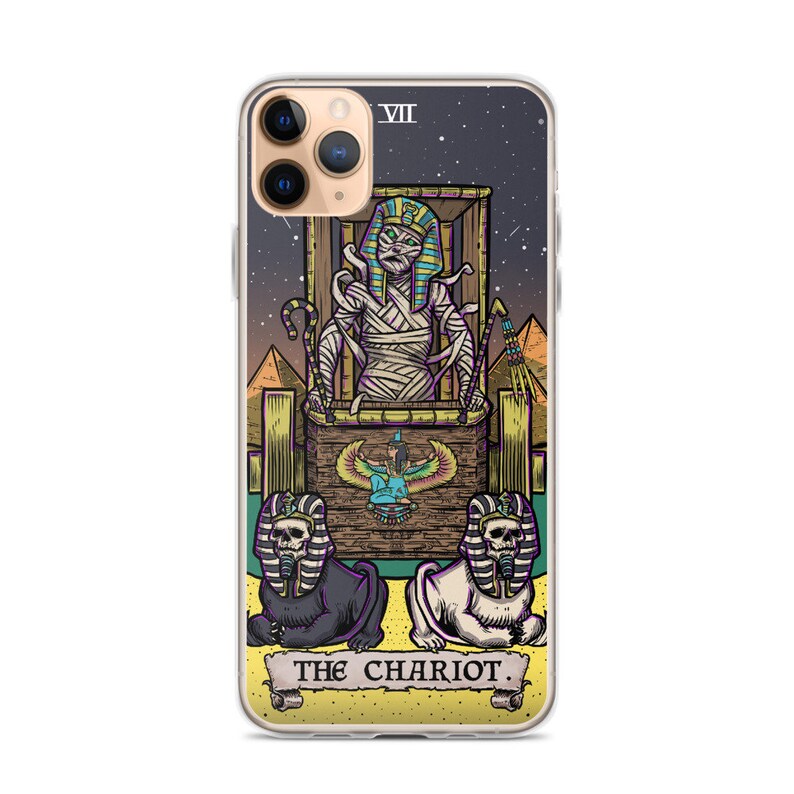 K&ouml;nnte beinhalten: Eine transparente Handyh&uuml;lle mit einer farbenfrohen Illustration der Chariot-Karte aus dem Tarot-Deck. Die Karte zeigt eine mumienartige Figur in einem Wagen, der von zwei sphinxartigen Kreaturen gezogen wird. Die Karte ist vor einem sternenklaren Nachthimmel platziert und der Text "THE CHARIOT" ist unten aufgedruckt.