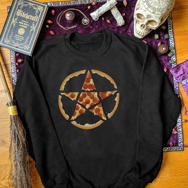 May include: Black sweatshirt featuring a pepperoni pizza slice design in the shape of a pentagram. The pizza pentagram is surrounded by a crust circle. The sweatshirt is a crew neck style.