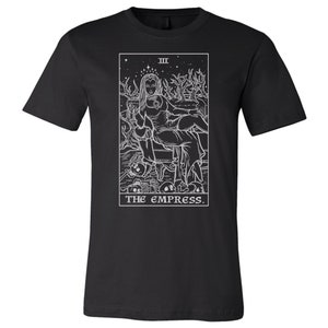 May include: Black t-shirt with a white outline of the Empress tarot card. The card features a woman sitting on a throne with a crown and a star above her head. The text "III THE EMPRESS." is below the image.