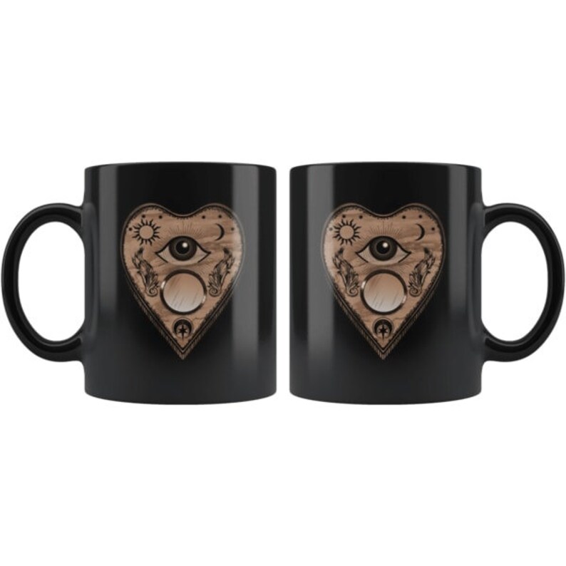 Puede incluir: Dos tazas de cer&aacute;mica negra con un dise&ntilde;o en forma de coraz&oacute;n. El dise&ntilde;o presenta un ojo, un sol, una luna y otros s&iacute;mbolos con un acabado de madera. Las tazas son id&eacute;nticas y aptas para bebidas fr&iacute;as o calientes.