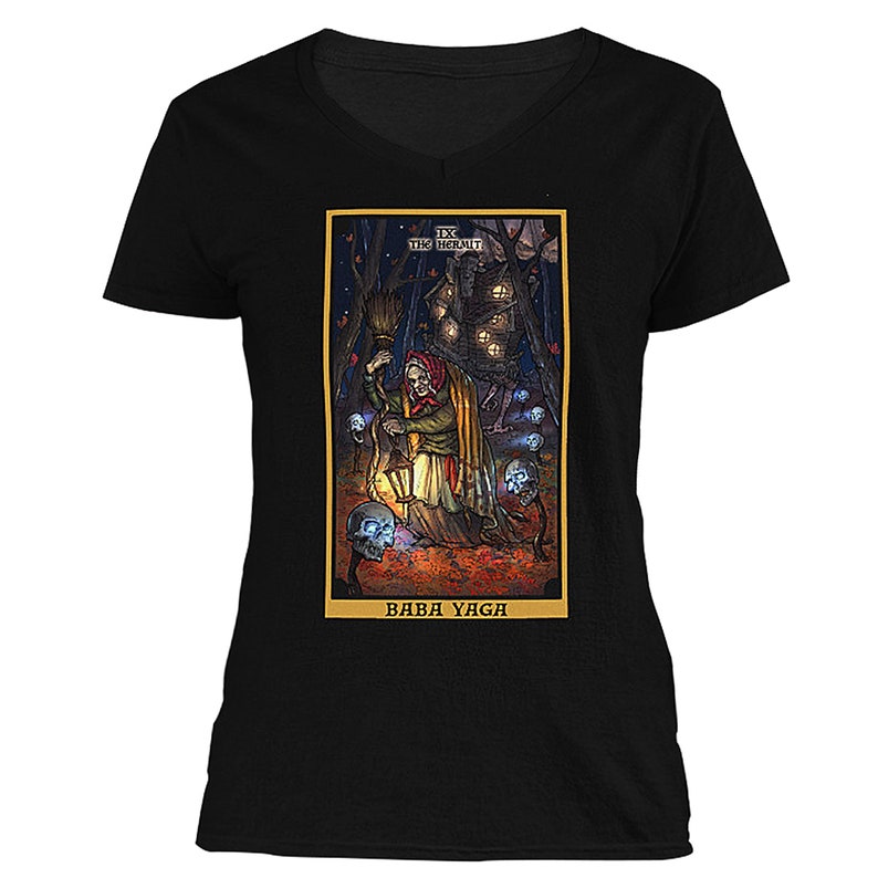 May include: A black t-shirt with a colorful illustration of Baba Yaga, a witch from Slavic folklore, holding a lantern and a broom. The illustration is surrounded by a gold frame and includes the text "IX THE HERMIT" and "BABA YAGA".