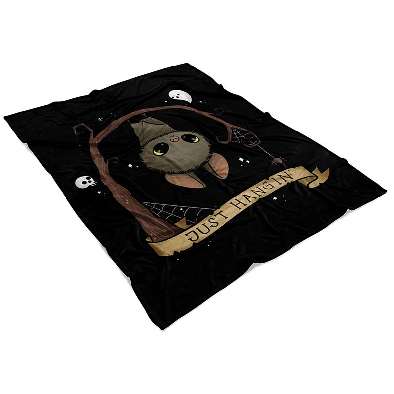 Pu&ograve; includere: Coperta in pile nero con un pipistrello marrone appeso a un ramo con il testo "Just Hangin'" su uno stendardo marrone.